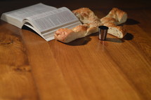 open Bible, cross shaped bread, and cup of communion wine 