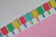 colorful row out of self made, crafted sponge popsicles on top of  pink paperboard as thank you for the volunteer cleaning team in church or as decoration for the vacation bible school in the classroom