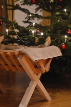 a manger in front of a Christmas tree 