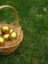 Basket of gold Easter eggs in the grass.
