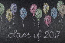 chalk on slate with balloons and the words: class of 2017