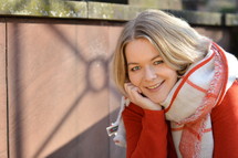 a smiling young woman in a scarf and red shirt 