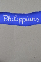 Philippians - torn open kraft paper over intense blue paper with the name of the letter from Paul to the Philippians