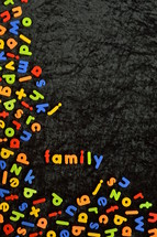 the word FAMILY written with colorful magnetic letters on black ground. 
