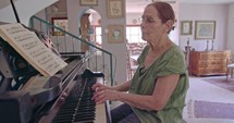 Old woman playing a grand piano at her home
