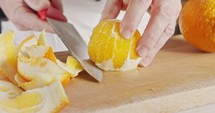 Close up of a chef knife peeling and slicing an orange