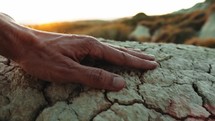 Hand Touching Cracked Dry Ground