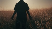 Young man walking through a field.  Standing in a field during Sunset.
