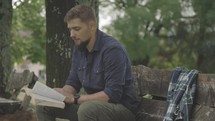 Close up of hands and pages as young man hold and reads the Bible outside