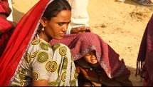 mother covering her child with a blanket in the desert 
