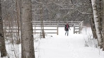 woman walking in falling snow on a farm 
