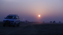 van driving on a dirt road in a desert 