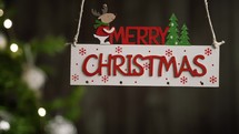 Merry Christmas sign hanging with tree on the background
