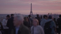 Unrecognizable Tourists on the rooftop of Galeries Lafayette Haussmann enjoying the sunset with the iconic Eiffel Tower and the city buildings of Paris in the background