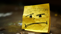 Sad face drawn on a yellow sticky note.