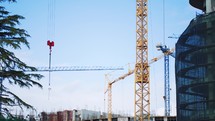 Construction of a high-rise building with a crane. Tower cranes against the blue sky. House under construction. The construction crane and the building against the blue sky.