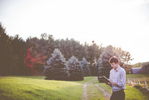 a man standing outdoors reading a Bible 