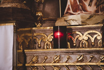 candle at the foot of a statue in a cathedral 