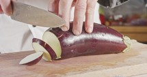 Slow motion close up of a chef knife slicing an Eggplant