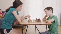 Young kids playing Chess on the living room table