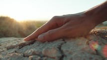 Hand Touching Cracked Dry Ground