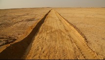 A dirt road cut through the desert.