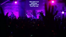 Silhouette of an audience with arms raised jumping at a worship concert.