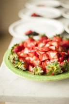 cut strawberries on a paper plate 