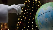 Santa tracing his road on the globe for Christmas 