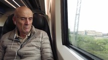 Elderly man is traveling by train and watching out