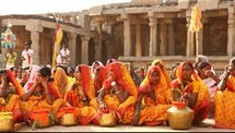 women in India sitting on the ground in front of a temple 