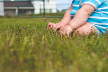 infant boy sitting in green grass 