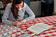 A woman writing Bible verses down to put in an Advent calendar 
