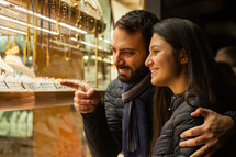 young couple choosing wedding rings while smiling while doing shopping in Florence.