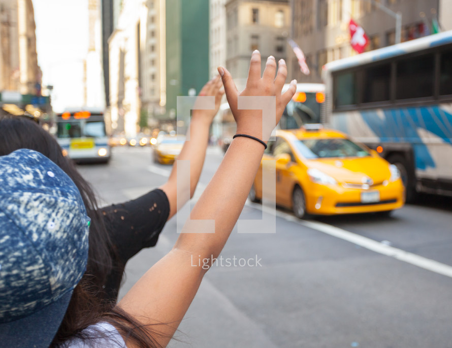 Tourists call a yellow cab in Manhattan with typical gesture with arm up