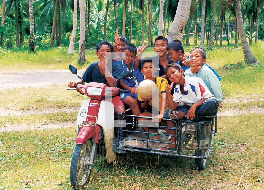 Eight kids in on a motorbike and side car carriage 