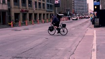 man riding a bike across a city street and people using a crosswalk