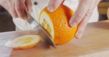 Close up of a chef knife peeling and slicing an orange