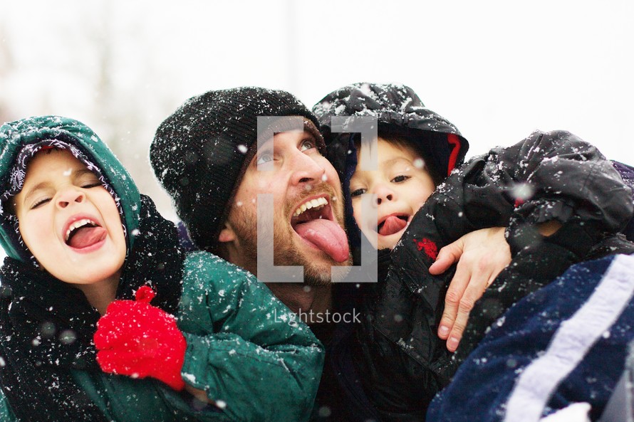 A father and his two sons playing in snow