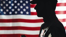American soldier prays with background flag