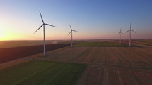 Aerial view of landscape with types of fields and wind turbines at sunset. Wind turbines producing clean renewable energy.