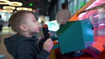 Boy playing on the kids game machine at an amusement park. Child playing on the kids game machine.