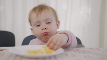 Cute baby eating an orange next to a table