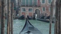 The atmosphere of narrow canals in the city of Venice, with many bridges and small boats parked.