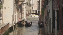 The atmosphere of narrow canals in the city of Venice, with many bridges and small boats parked.