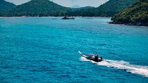 Small boat drives on crystal clear blue water to exotic island. Boat trip. Long Tail Boat. 