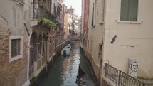 The atmosphere of narrow canals in the city of Venice, with many bridges and small boats parked.