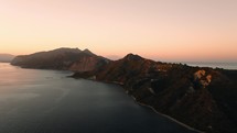 Aerial view above the mountains on an island surrounded by the sea during sunset in Greece