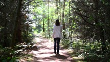 a woman walking alone on a path through the woods 