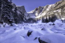 Snow drifts form over the boulders along the frozen shoreline of Dream lake, a popular high altitude lake located in Rocky Mountain National Park